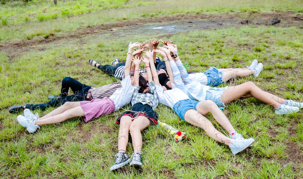 Group of Friends Form in Circle While Lying on the Grass While Hands on Top